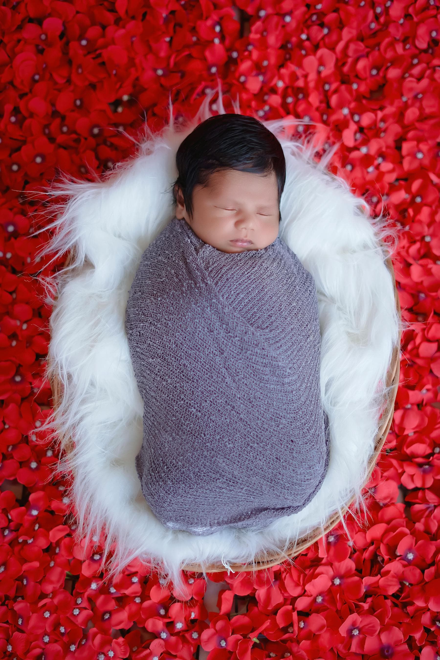 Newborn baby wrapped and sleeping peacefully in a studio setup.