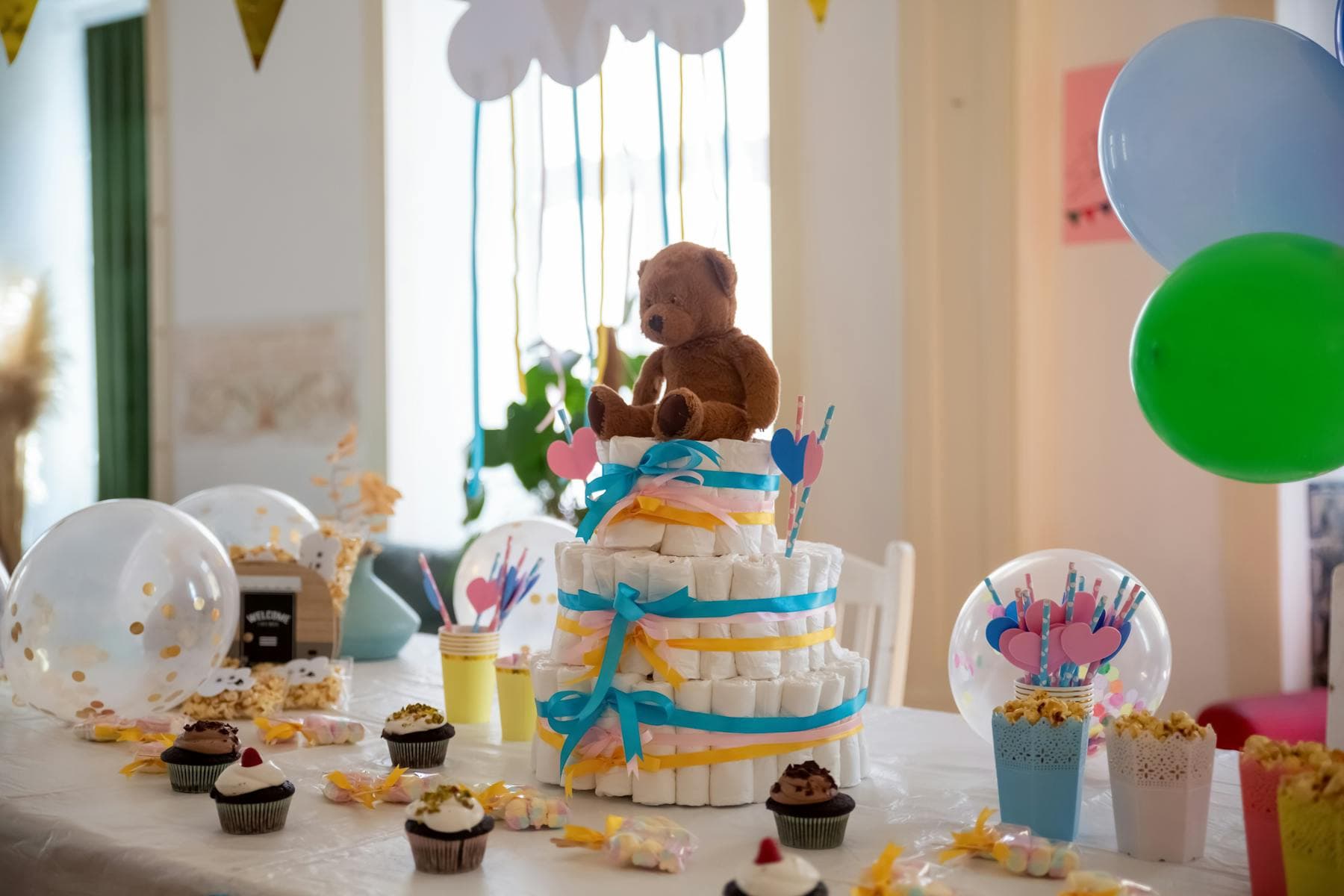 Styled baby shower table with cake, balloons, and party decor.